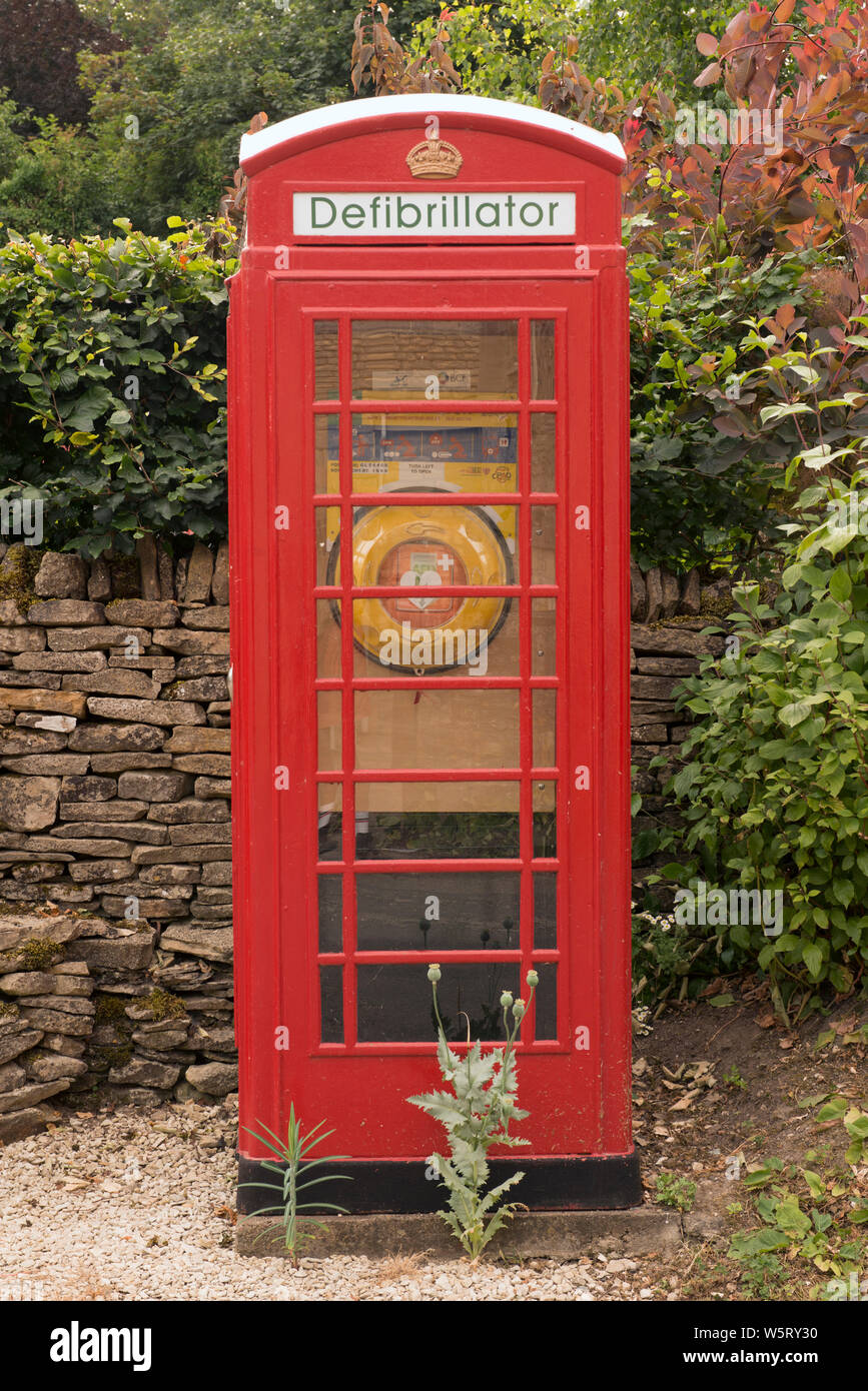 K6 teléfono caja utilizada para albergar un defribrillator en Compton Abdale, Gloucestershire, Inglaterra Foto de stock