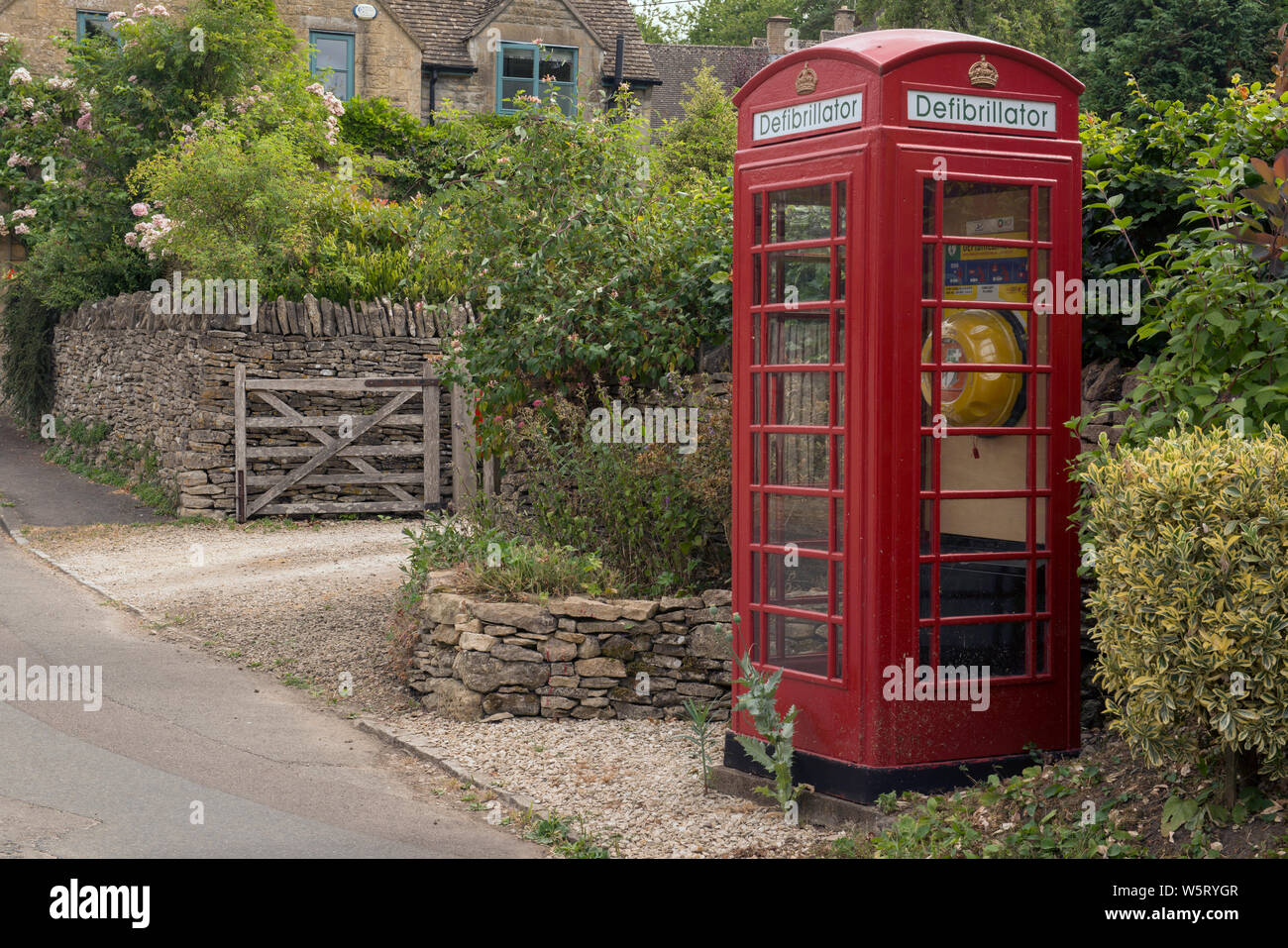 K6 teléfono caja utilizada para albergar un defribrillator en Compton Abdale, Gloucestershire, Inglaterra Foto de stock