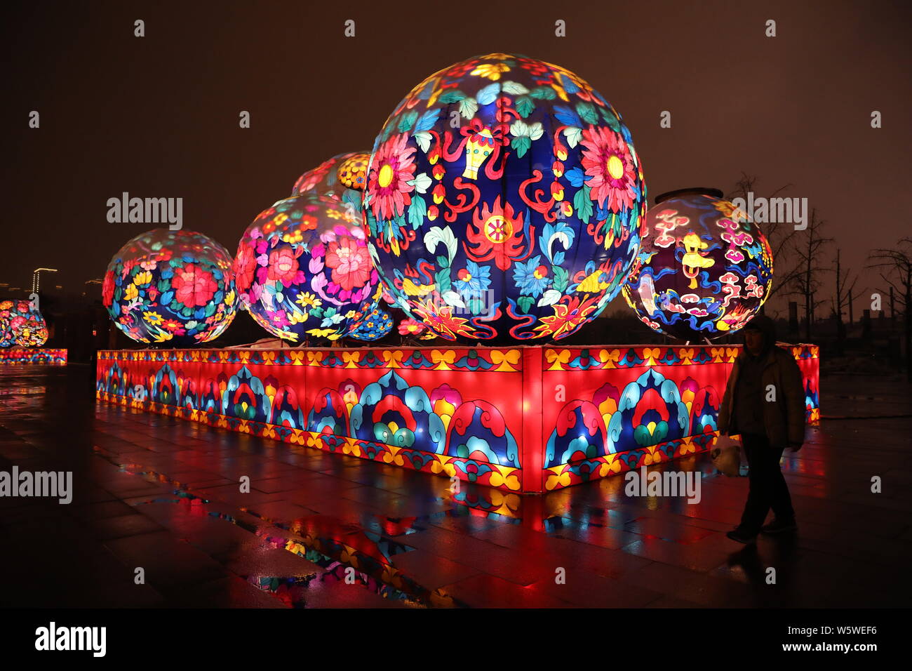 Los peatones pasa por una instalación de arte iluminada y colorida con la forma de elementos tradicionales chinos para marcar el próximo año nuevo en un r Foto de stock