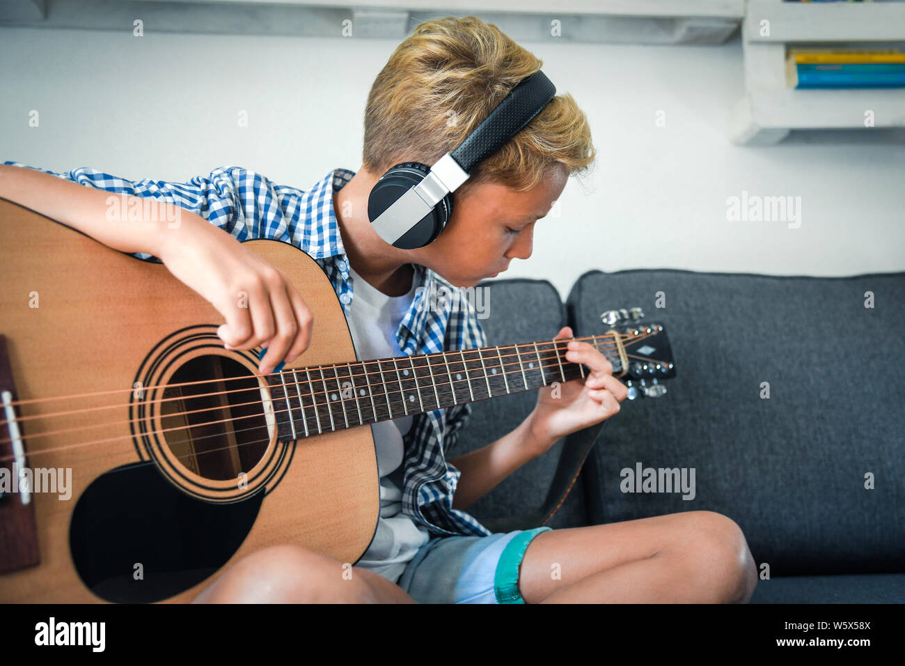 Close Up retrato de hermosa joven tocando la guitarra acústica con  auriculares. Ejercicios de estudiante solo en casa. Moda niños caucásicos  reproduce instrumentos Fotografía de stock - Alamy