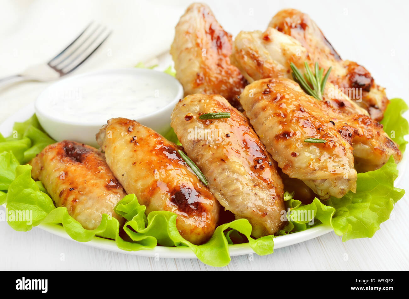 Alas de pollo a la plancha sobre hojas de lechuga y salsa de mesa de Alas de pollo a la plancha sobre hojas de lechuga y salsa de mesa de