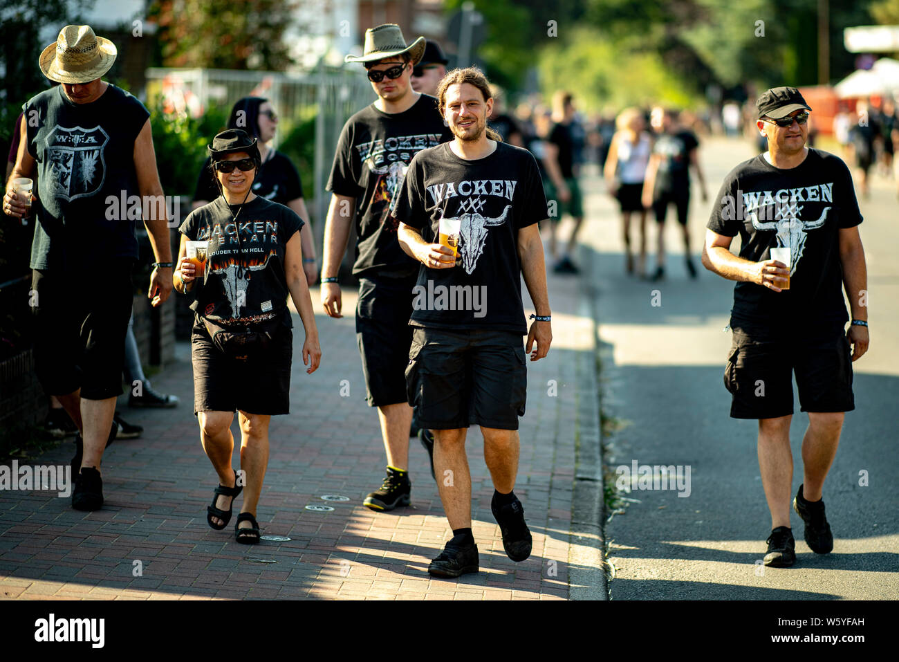 Wacken, Alemania. El 30 de julio, 2019. Los visitantes de la Wacken-Festival caminar a lo largo de la calle principal de la villa. El viaje al Festival Meatö más grande en el mundo, según los organizadores está en pleno apogeo. Crédito: Axel Heimken/dpa/Alamy Live News Foto de stock