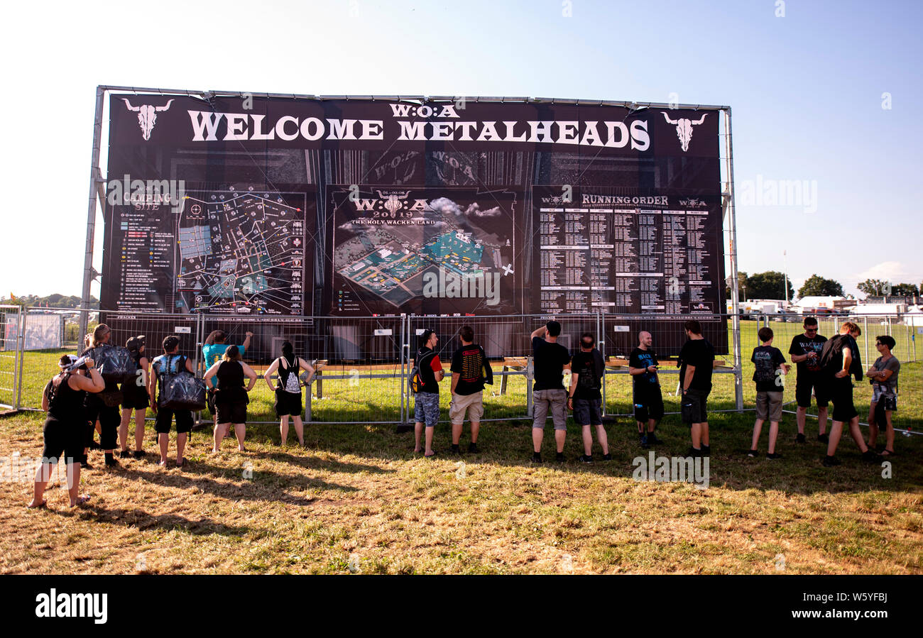 Wacken, Alemania. El 30 de julio, 2019. Los visitantes del festival de Wacken delante de un mapa de los terrenos del festival. El viaje al Festival Meatö más grande en el mundo, según los organizadores está en pleno apogeo. Crédito: Axel Heimken/dpa/Alamy Live News Foto de stock