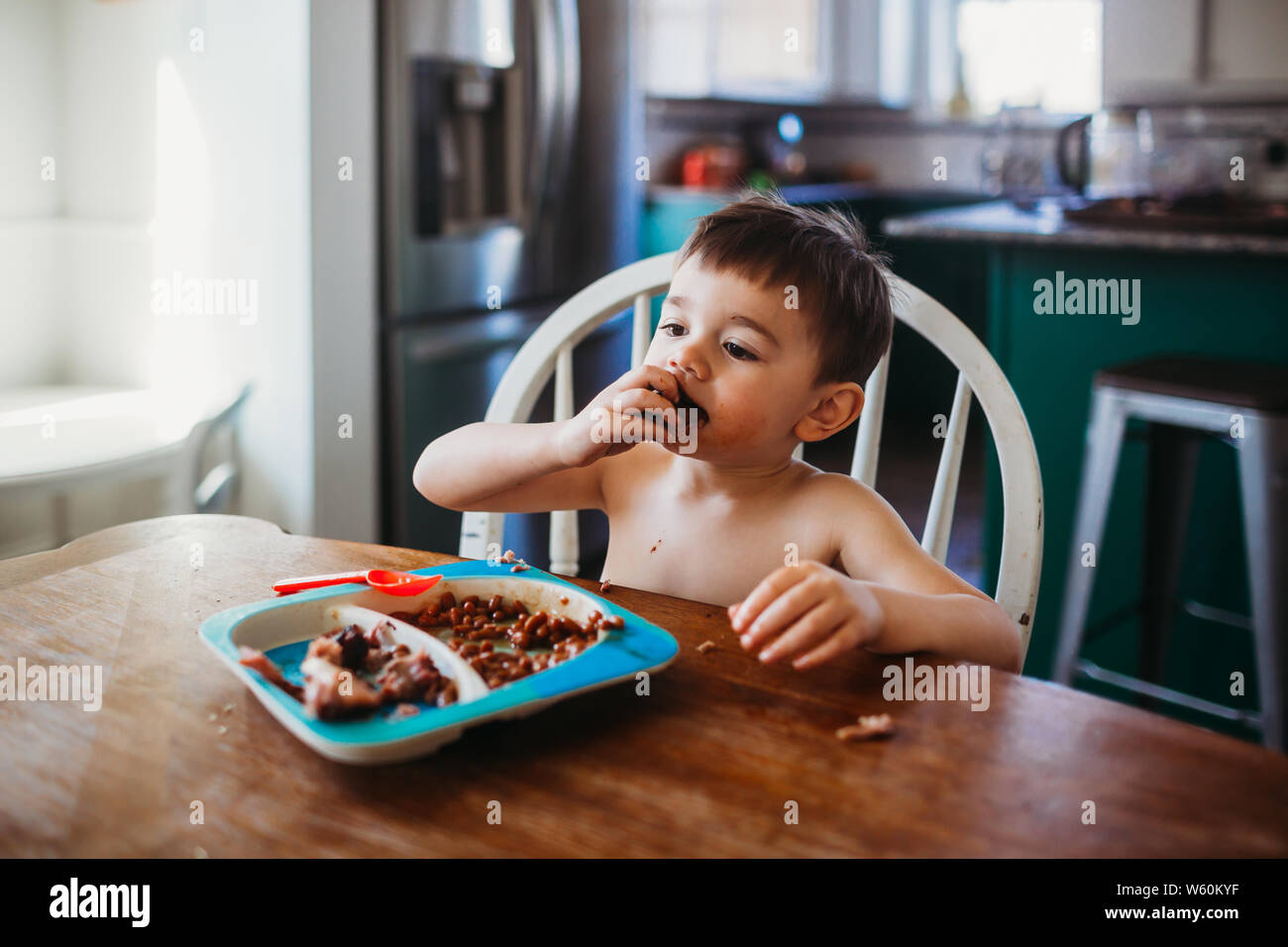 Joven comiendo costillas mientras está sentado en la mesa de comedor Foto de stock