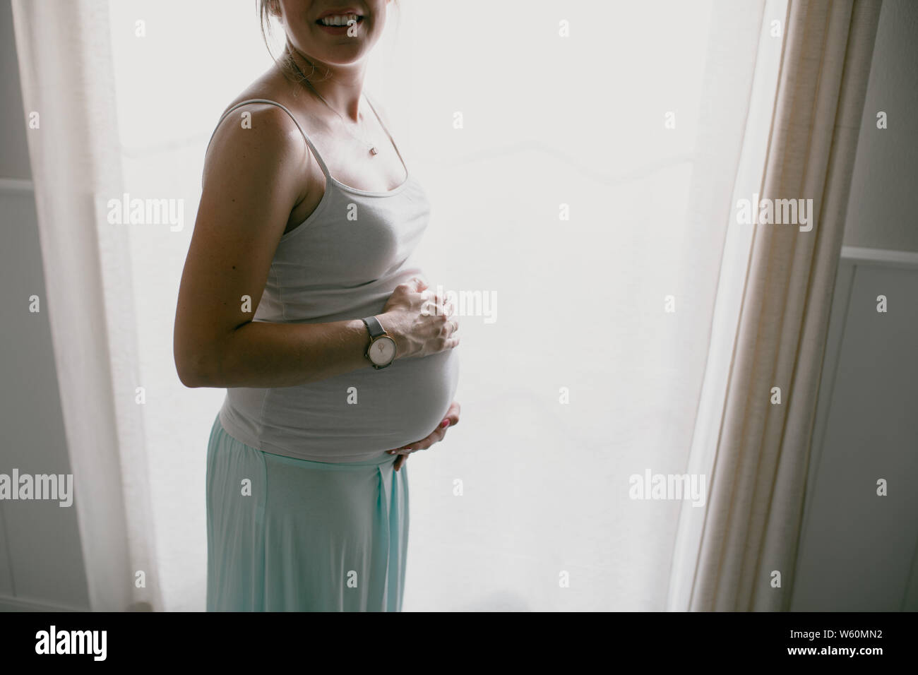 Retroiluminación de mujer embarazada tocando su vientre Foto de stock