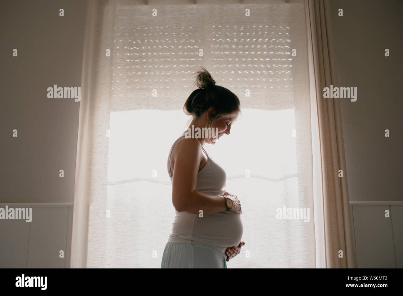 Retroiluminación de mujer embarazada tocando su vientre Foto de stock