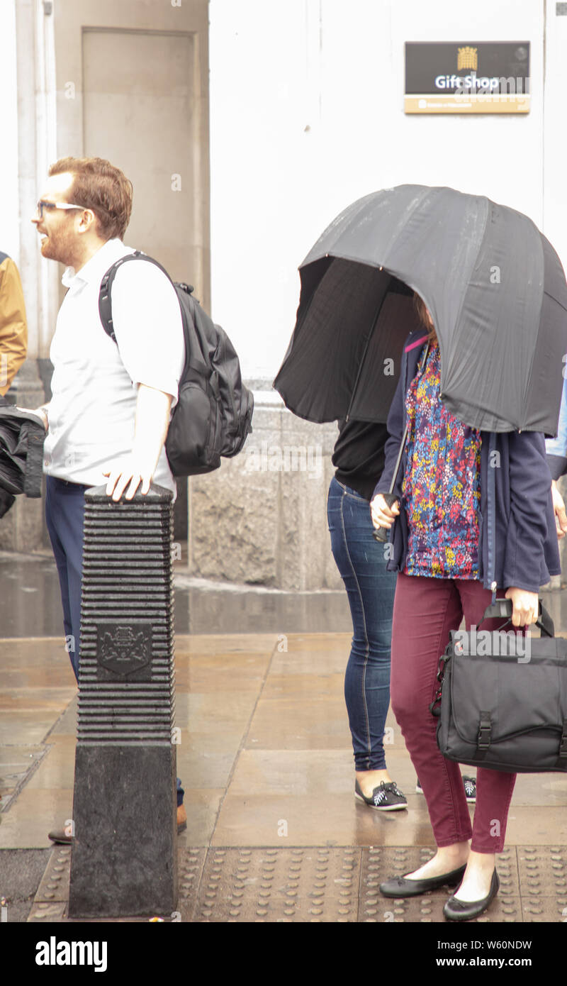 Londres, Reino Unido. El 30 de julio, 2019. Mujer con un paraguas cerrado a  los lados para mantener seco en la lluvia de Londres. Crédito: Joe Kuis:  Alamy / Noticias Fotografía de stock - Alamy