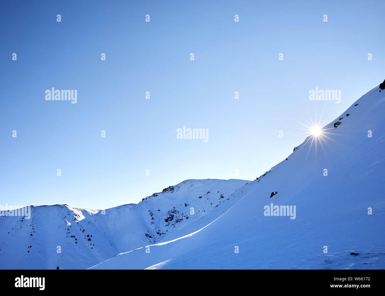 Sol en forma de estrella surge en las montañas con la nieve y los glaciares en invierno Foto de stock