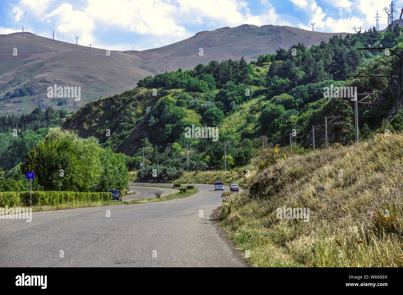 Carretera a través de la montaña entre los árboles que conduce a la alta montaña, el lago Sevan en Gegharkunik región de Armenia Foto de stock
