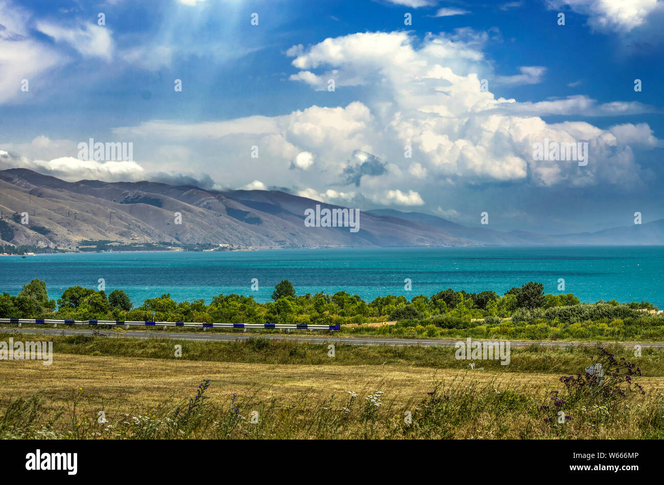 El lago Sevan de alta montaña, rodeado por las montañas de Geghama, está cubierto con nubes gruesas vista desde la carretera pasando a lo largo de la costa Foto de stock