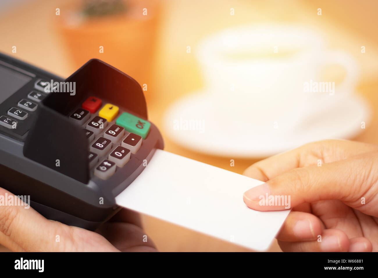 Concepto de pago con tarjeta de crédito. close-up mano insertar tarjeta de crédito ficticia con tarjeta en blanco blanco con una máquina de lectura de tarjeta en el terminal de punto de venta en el COF. Foto de stock