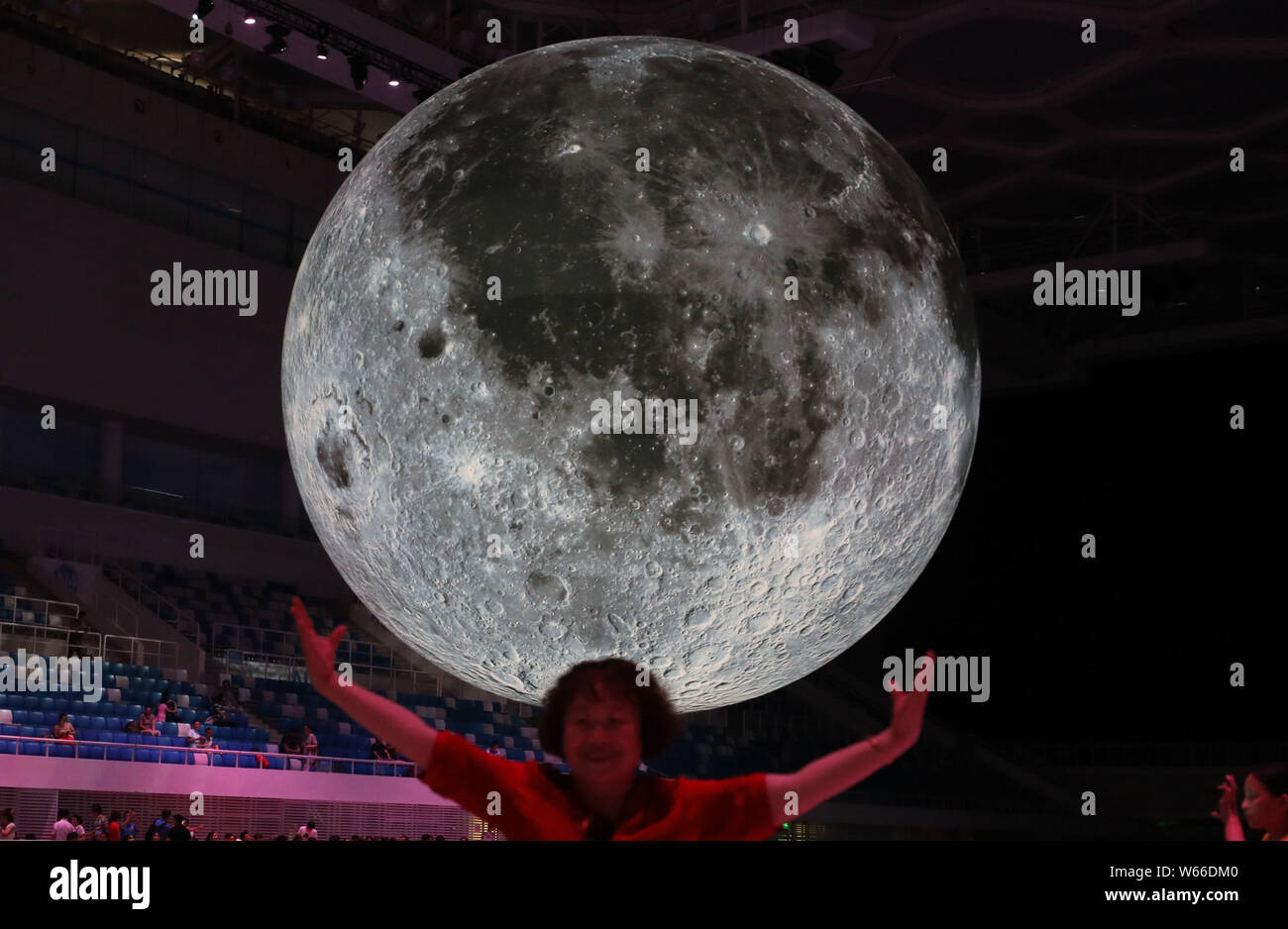Un visitante posa con un enorme toldo modelo para una fotografía durante una exposición sobre la luna, celebrado en el Centro Acuático Nacional o "Water Cube" en Beijing, China, Foto de stock