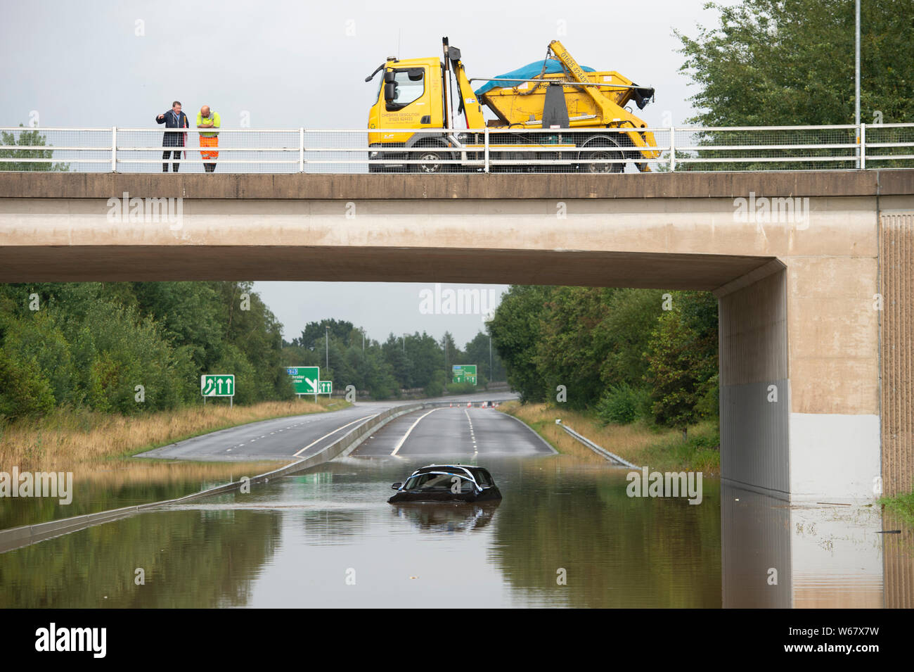 En Handforth, Reino Unido. El 31 de julio, 2019. Un automóvil BMW es abandonado en las aguas de la inundación en el aeropuerto de Manchester A555 carretera de alivio tras las fuertes lluvias durante días consecutivos. Crédito: Russell Hart/Alamy Live News Foto de stock