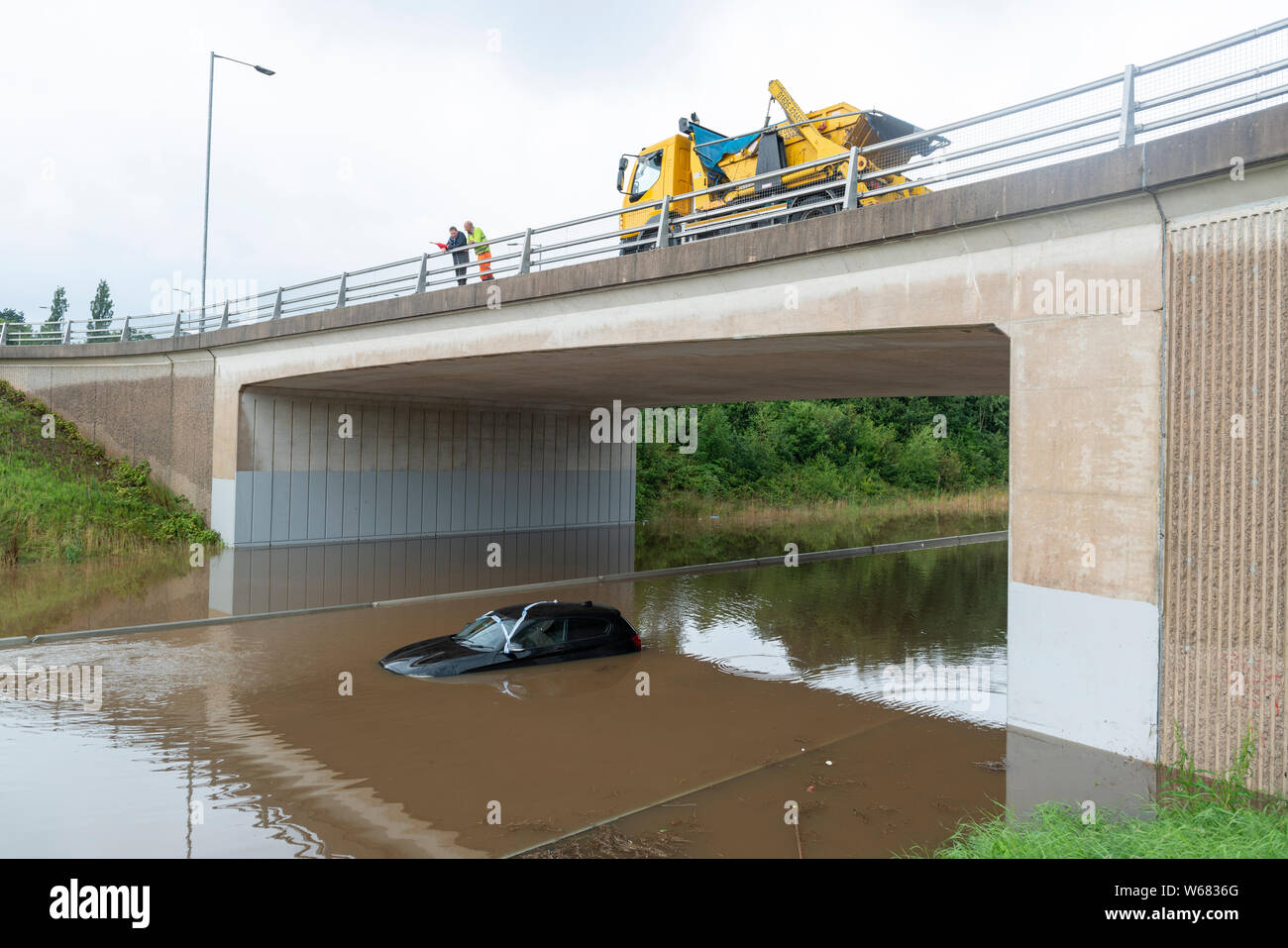 En Handforth, Reino Unido. El 31 de julio, 2019. Un automóvil BMW es abandonado en las aguas de la inundación en el aeropuerto de Manchester A555 carretera de alivio tras las fuertes lluvias durante días consecutivos. Crédito: Russell Hart/Alamy Live News Foto de stock