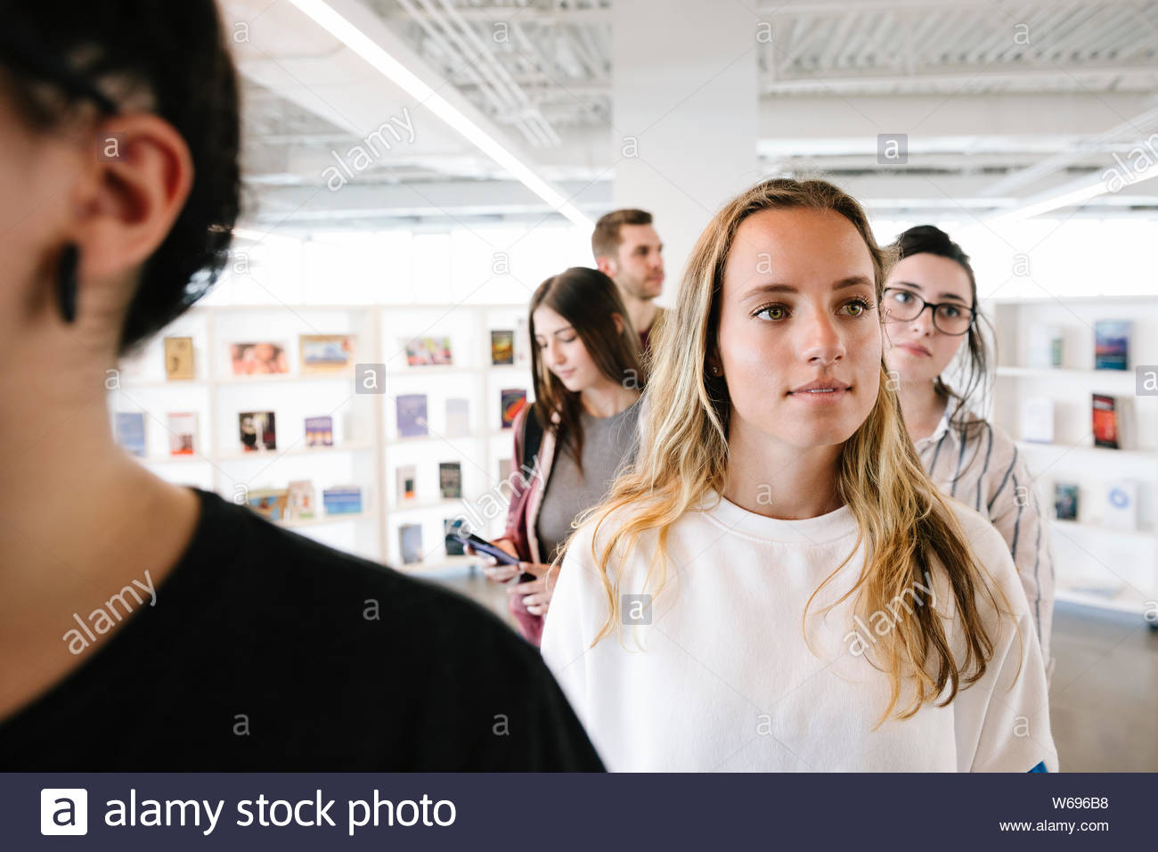 Estudiante en una línea usando el smartphone en la biblioteca de la universidad Foto de stock