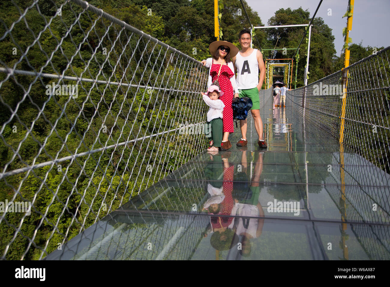 Los turistas posar para fotos mientras caminan sobre un puente colgante con fondo de cristal con una longitud de 199,9 metros y una altura máxima de 52 metros en una prima Foto de stock