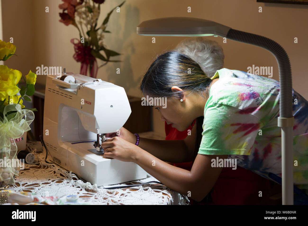 Una nieta ayuda a su abuela enhebrar la aguja de una máquina de coser Singer  en su casa en Warren, Indiana, EE.UU Fotografía de stock - Alamy