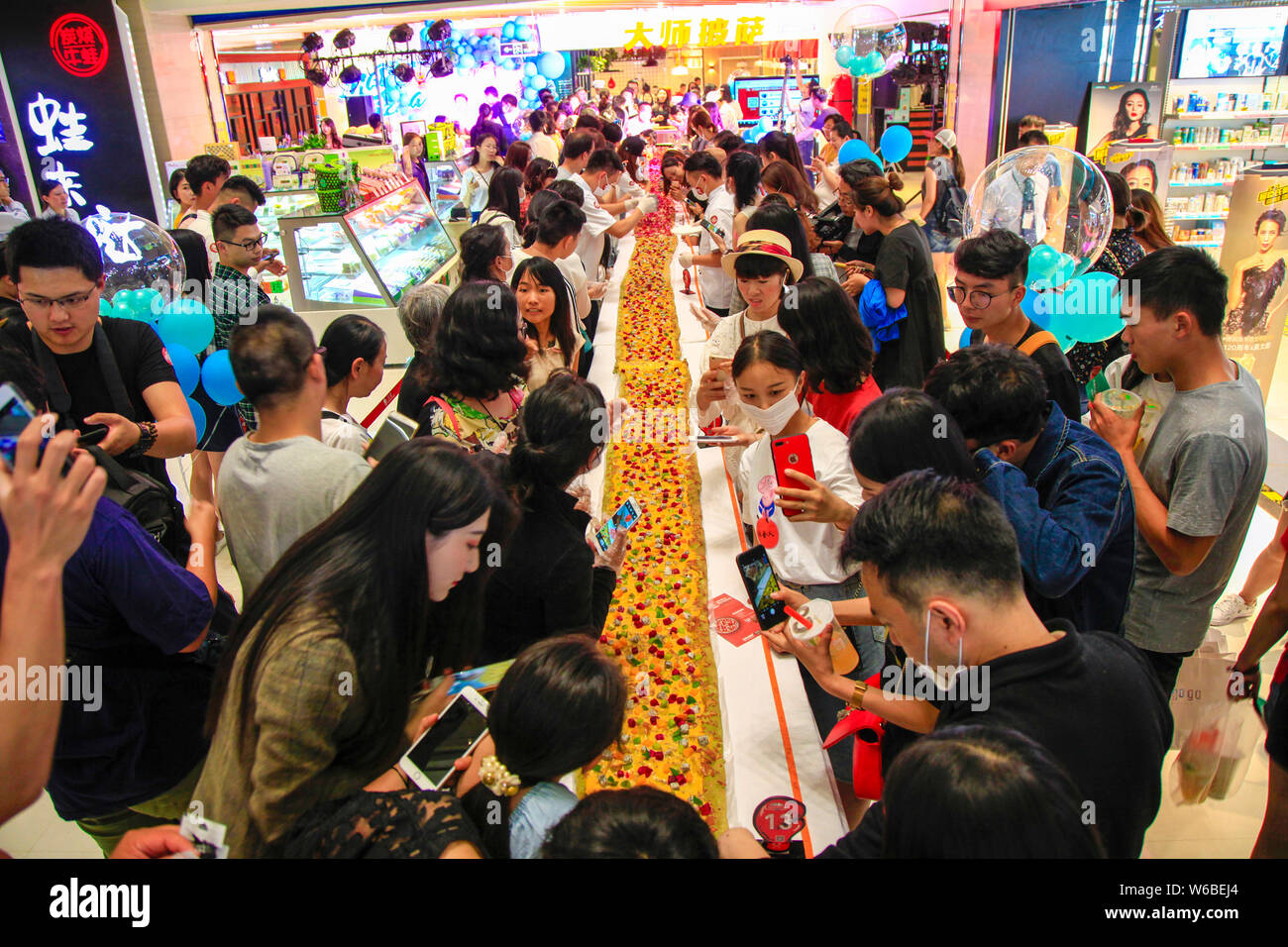 Los clientes probar la pizza más larga de China, que es de 13.14 metros de largo, en uno de los de la Internet China Días de San Valentín en un centro comercial en Kunming Foto de stock