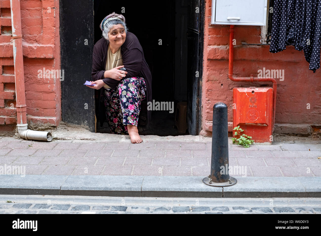 Una anciana mujer turca en un pañuelo de encuestas la actividad en la calle en frente de su casa en el centro de Estambul, Turquía Foto de stock