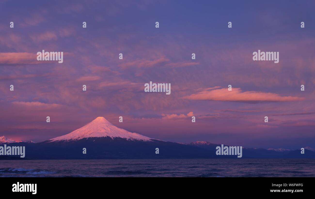 Hermosa puesta de sol de colores en el cielo y sobre el glaciar y la nieve del volcán Osorno Foto de stock