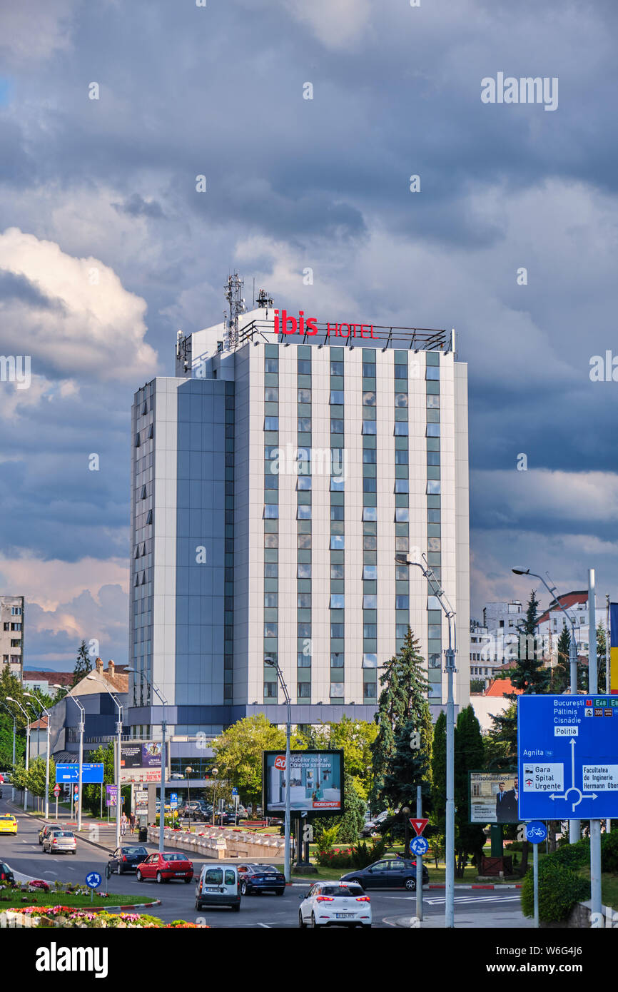 Sibiu, Rumania - Julio 11, 2019: Ibis hotel cerca del centro histórico / Downtown, con nubes de tormenta en la distancia. Ibis es un hotel internacional c Foto de stock