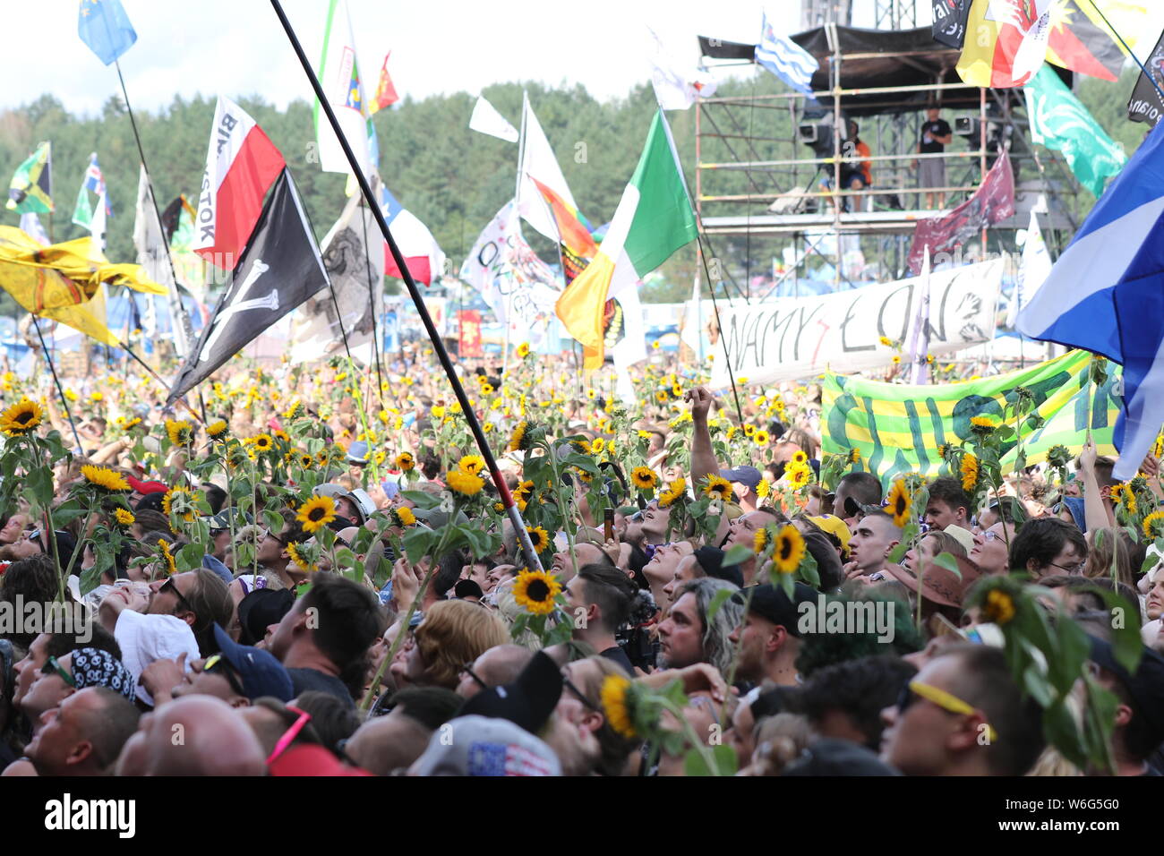 Kostrzyn, Polen, 1 de agosto de 2019, la muchedumbre con girasoles en frente del escenario principal. 25. Pol'y'Rock Festival es el mayor festival no comerciales en Europa. Este año el festival tendrá lugar del 1 al 3 de agosto en la ciudad de Kostrzyn nad Odra en Polonia occidental. Foto de stock