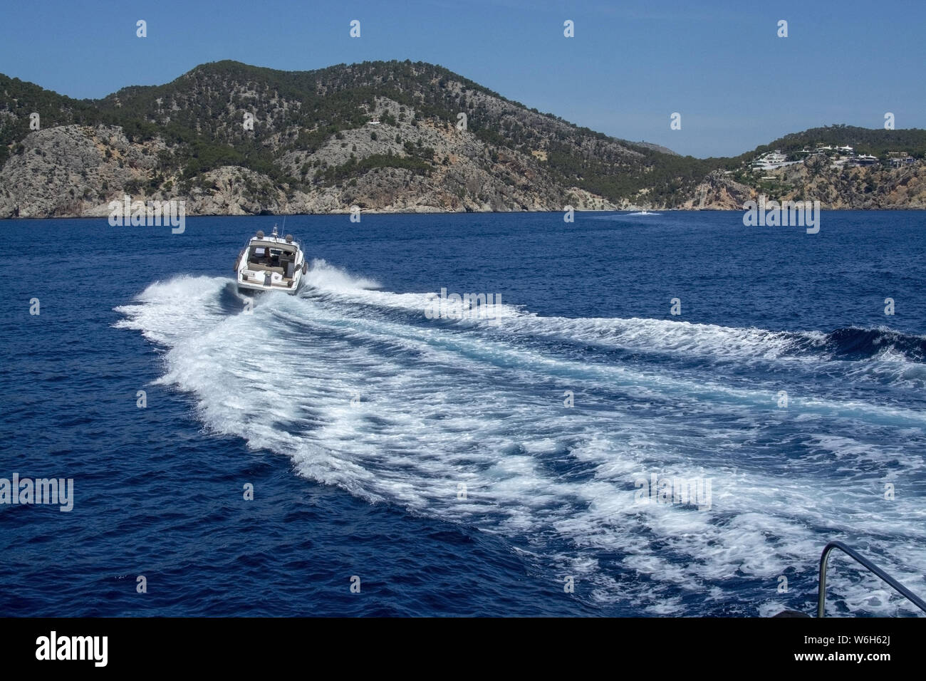 Barco de motor acelerando la espumosa Haciendo olas en el agua azul del Mediterráneo en un día soleado de verano en Mallorca, España. Foto de stock