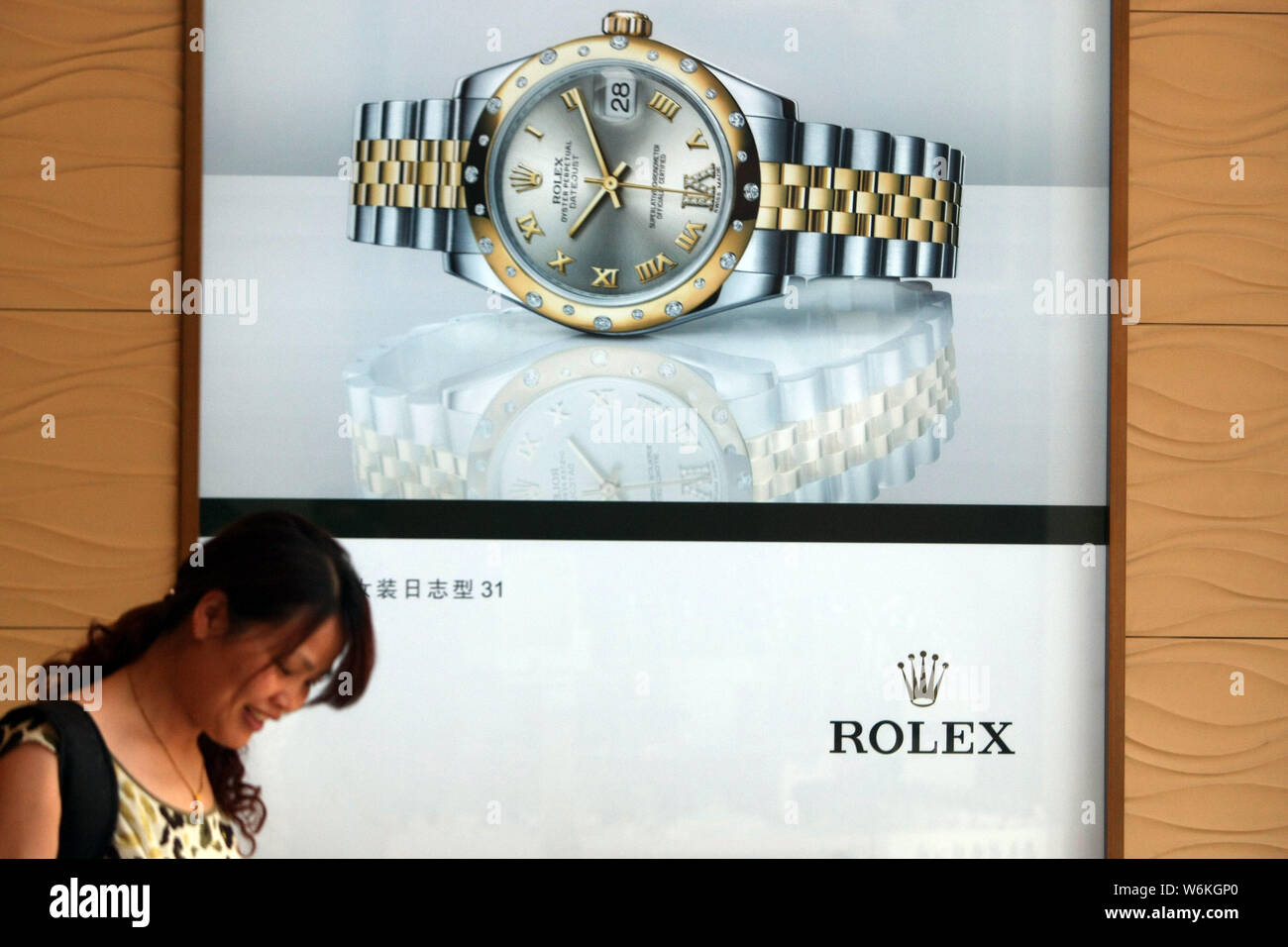 --FILE--un peatón camina pasado un anuncio de Suiza Rolex relojero de lujo en Shanghai, China, 28 de mayo de 2013. Los relojeros de la industria maj Foto de stock