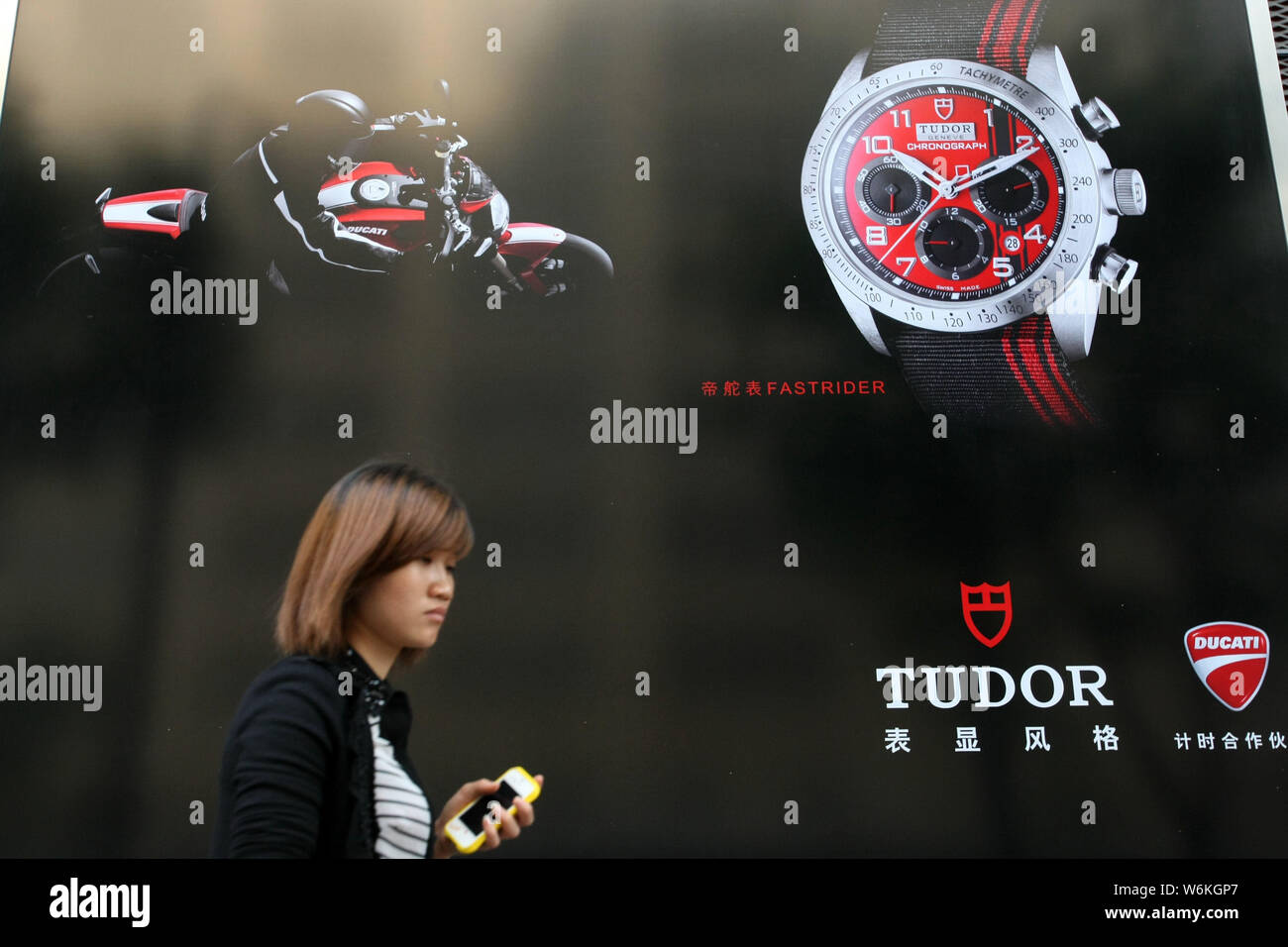 --FILE--un peatón camina pasado un anuncio de Tudor, una marca de relojes Rolex, en Shanghai, China, 28 de mayo de 2013. Los relojeros de la industria Foto de stock