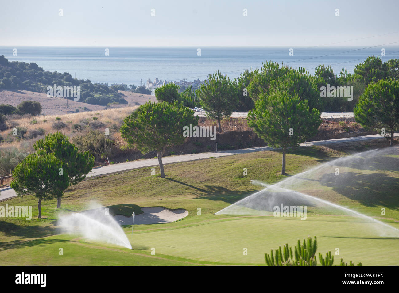 Sistema de riego Aspersores trabajando en el verde del campo de golf. La Costa del Sol, Málaga, España Foto de stock