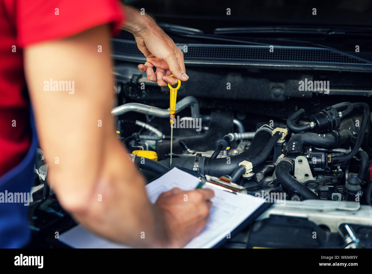 Coche - Inspección y mantenimiento mecánico revise el nivel de aceite del motor y la escritura en la lista Foto de stock