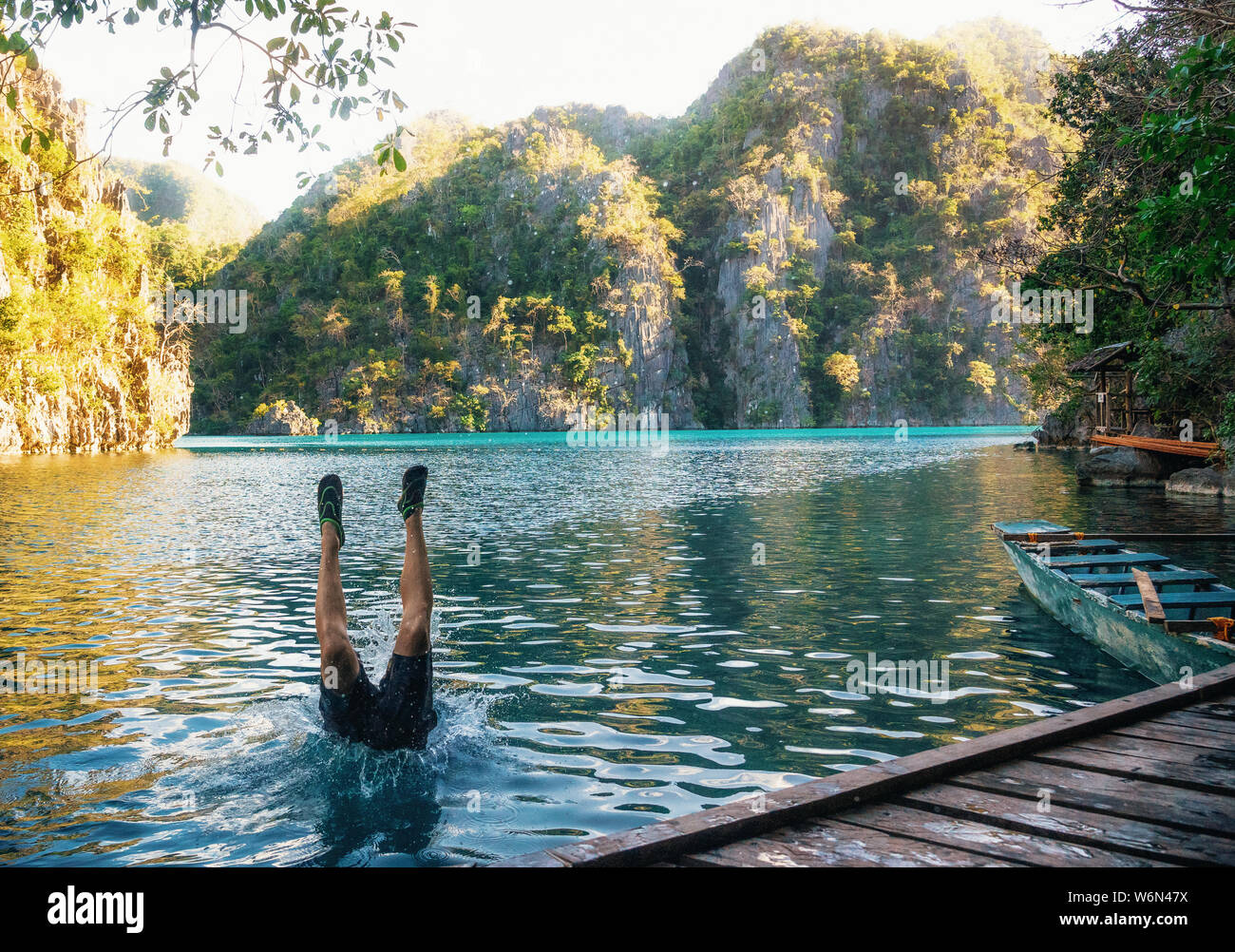 Joven salta al lago. Piernas sobresalen del agua. El Kayangan Coron, Lago, Filipinas Foto de stock