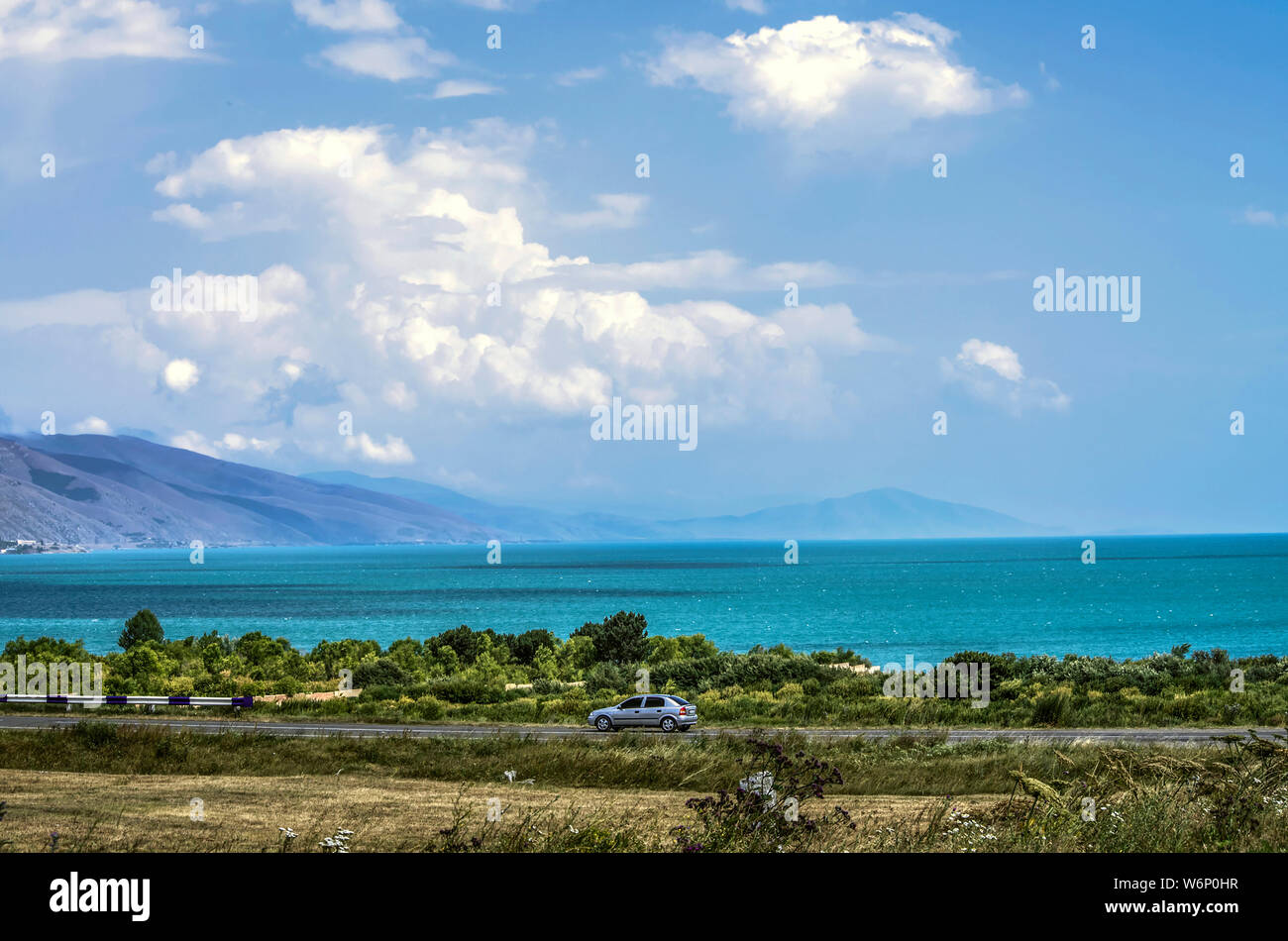 La autopista que pasa a lo largo de la costa de la costa azul del lago Sevan alpino a una altitud de 1900 metros sobre el nivel del mar, en las montañas de Armenia Foto de stock