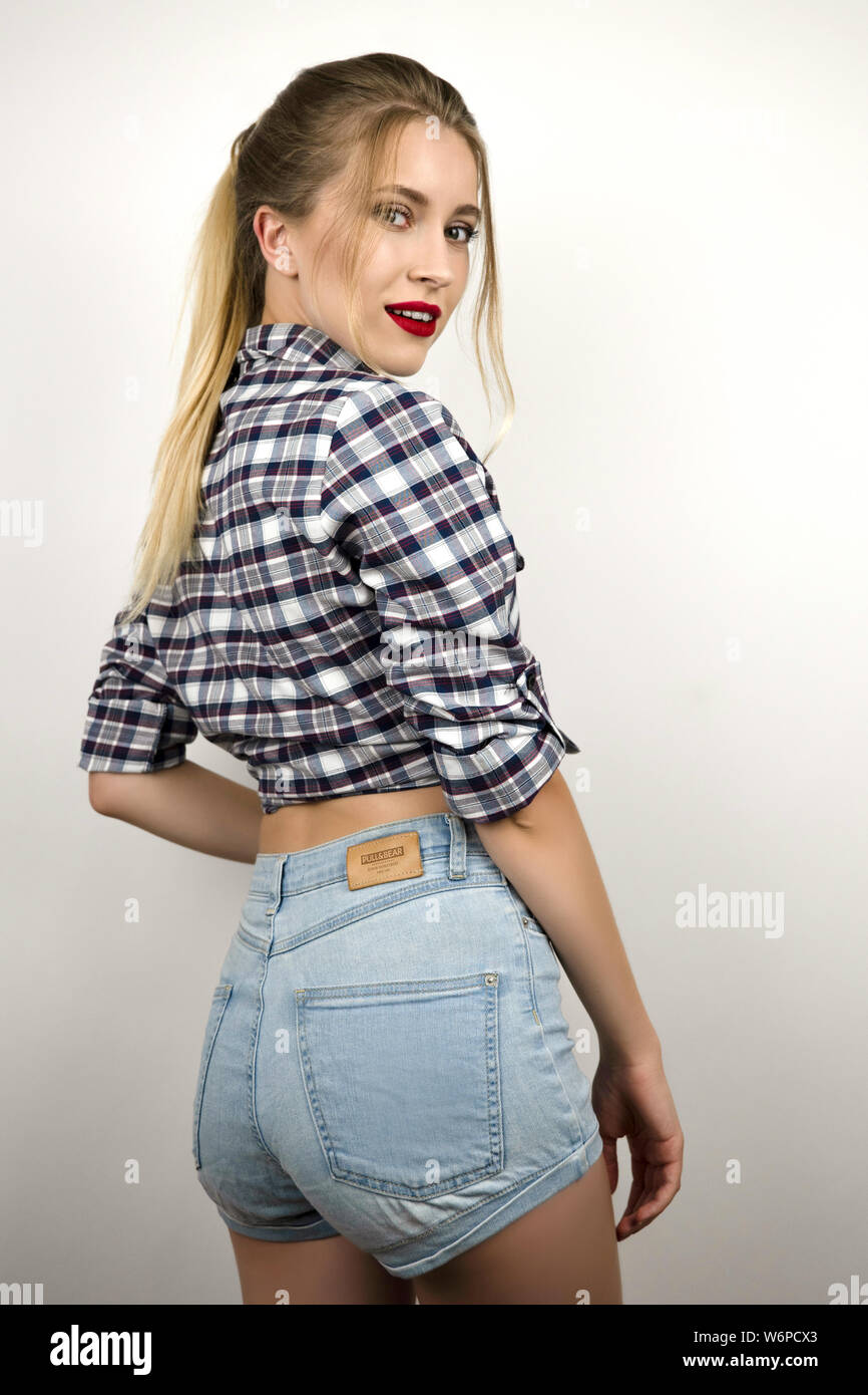 Joven rubia hermosa mujer vistiendo la moda denim shorts y camisa a cuadros  para la tienda de ropa fondo blanco aislado Fotografía de stock - Alamy