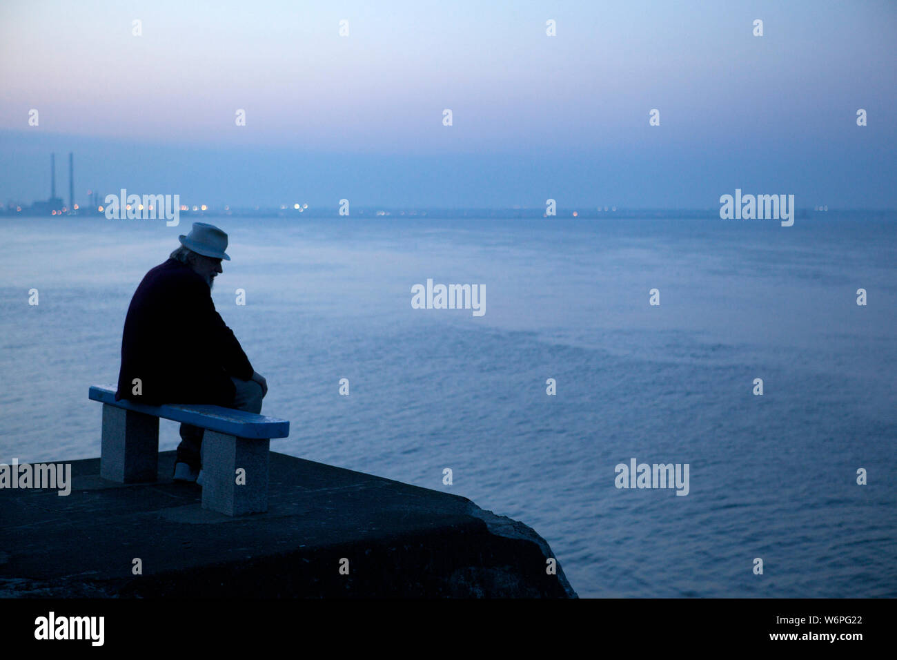 Anciano sentado en un banco en el mar Foto de stock