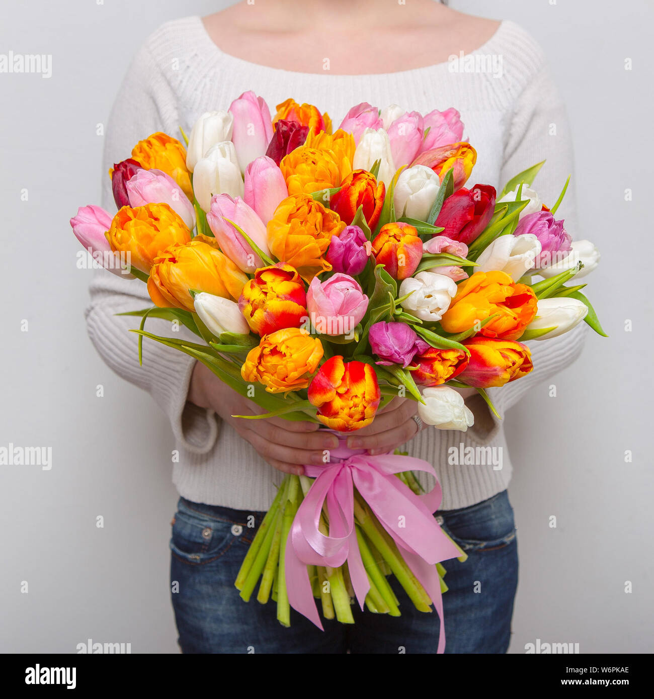 Florist muy bonita mujer sosteniendo un hermoso ramillete de flores  florecen coloridos tulipanes frescas hojas sobre la pared blanca de fondo  Fotografía de stock - Alamy