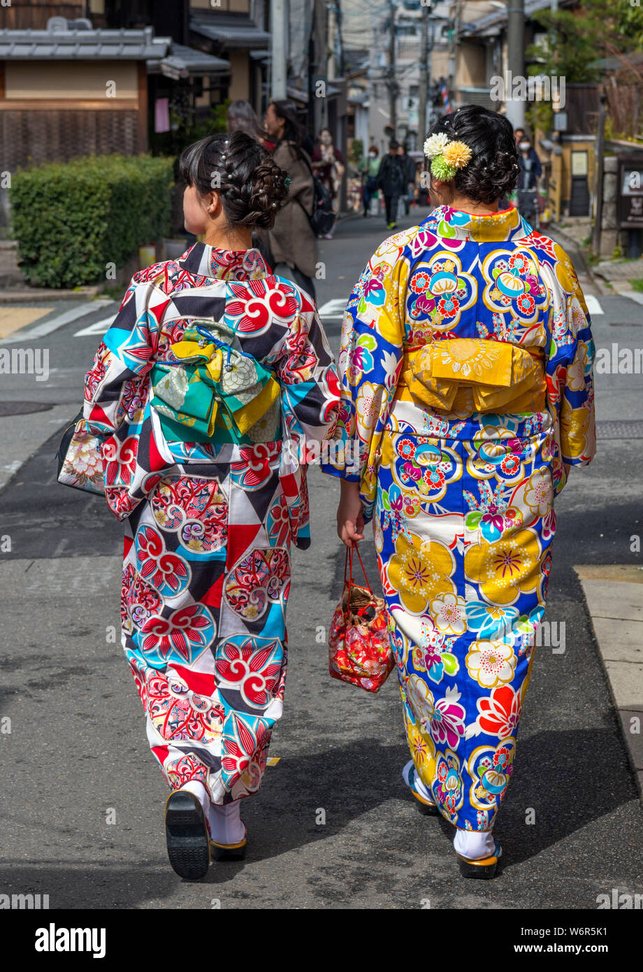 Dos jóvenes japoneses, vistiendo kimonos tradicionales, caminando por una calle en el distrito Gion, Kioto, Japón Foto de stock