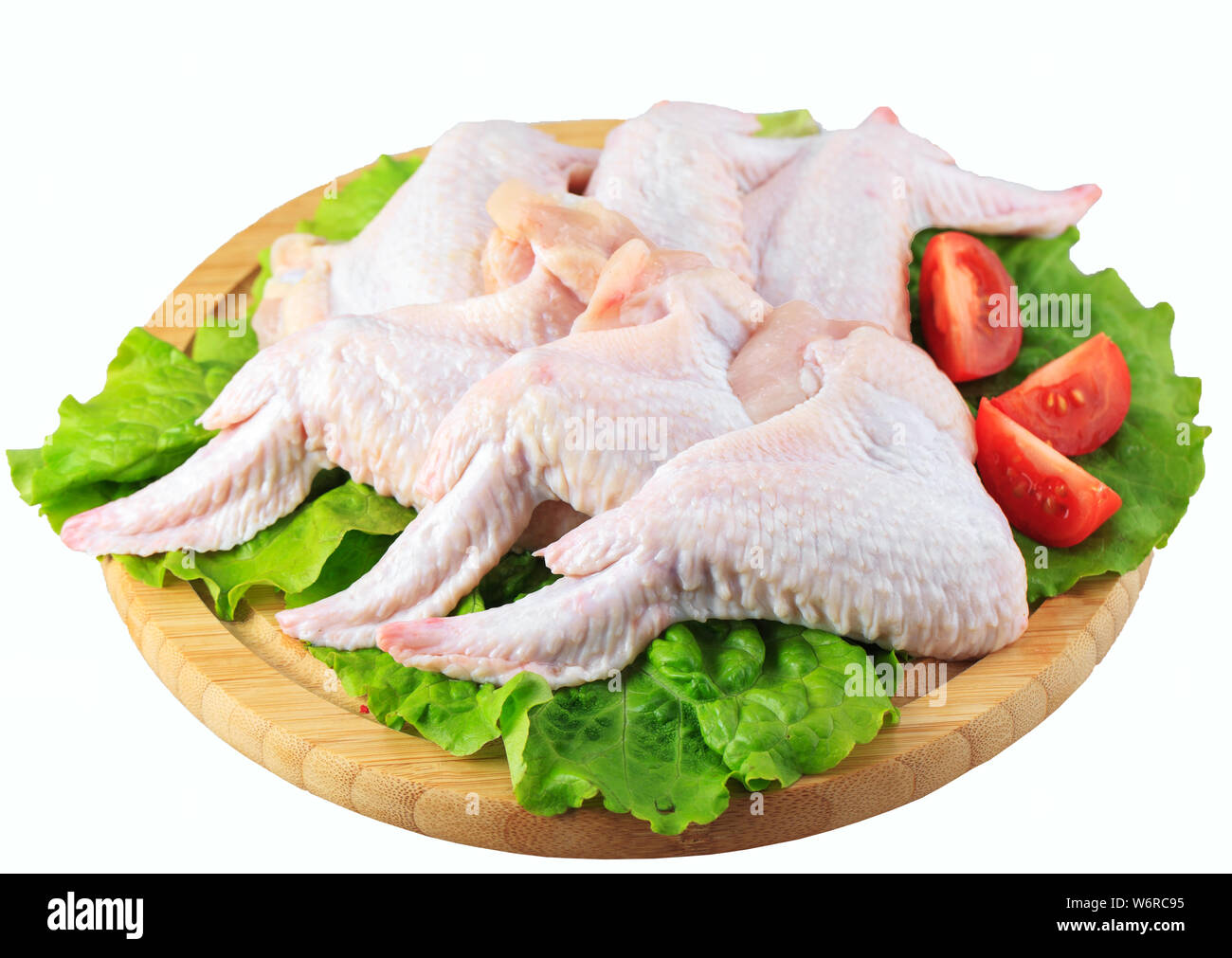 Alas de pollo cruda sobre una tabla de madera sobre fondo blanco