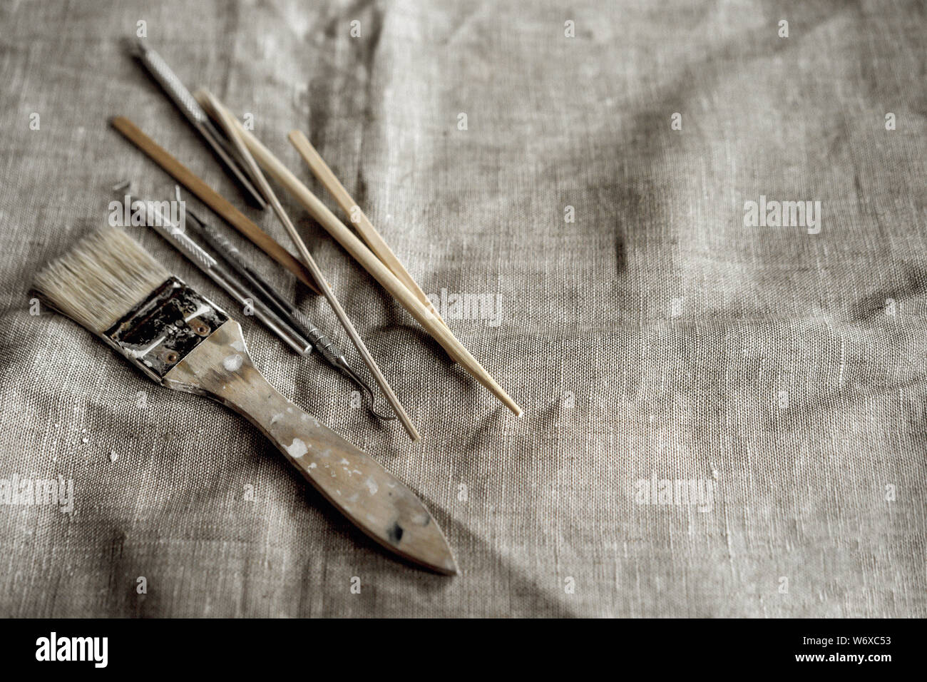 Herramientas de arcilla gris sobre lienzo. Cepillo, palos de madera, pilas, espátulas metálicas Foto de stock
