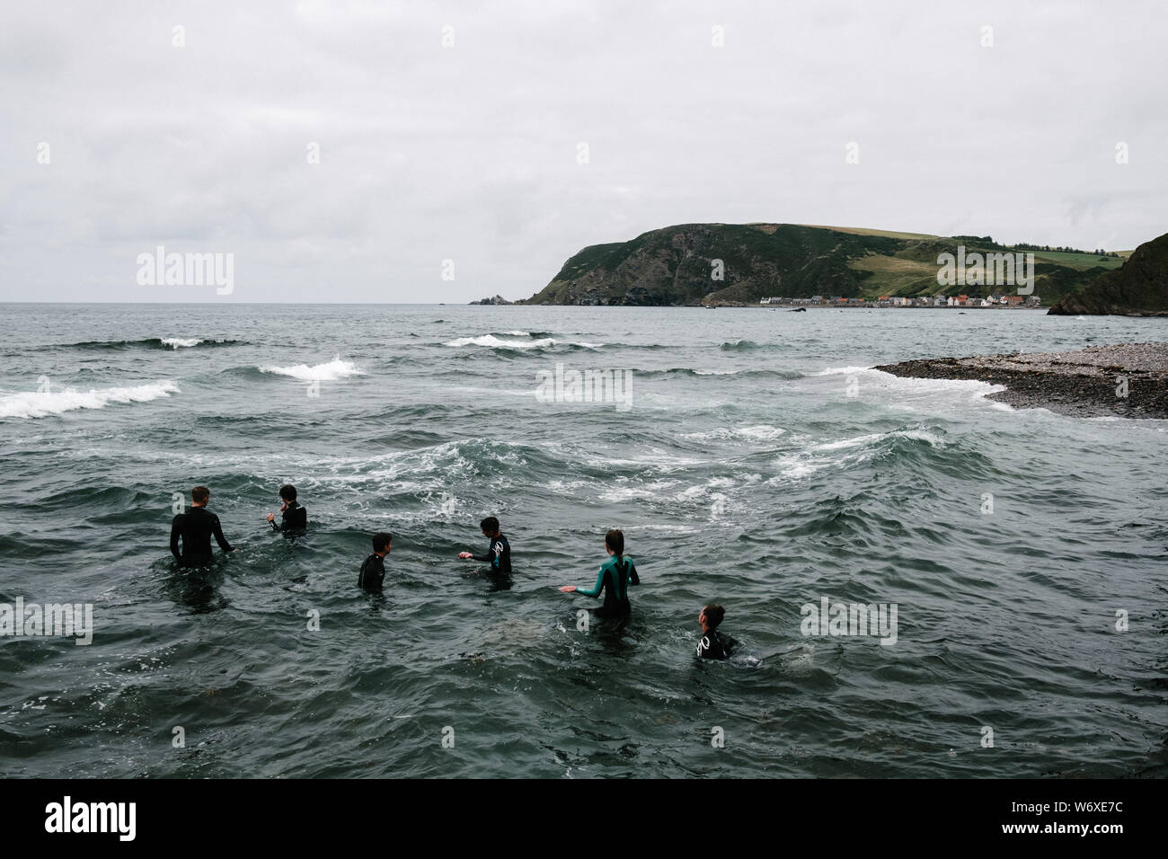Un grupo de seis adolescentes en trajes de nadar en el mar en el norte de la ciudad escocesa de Gamrie. Foto de stock