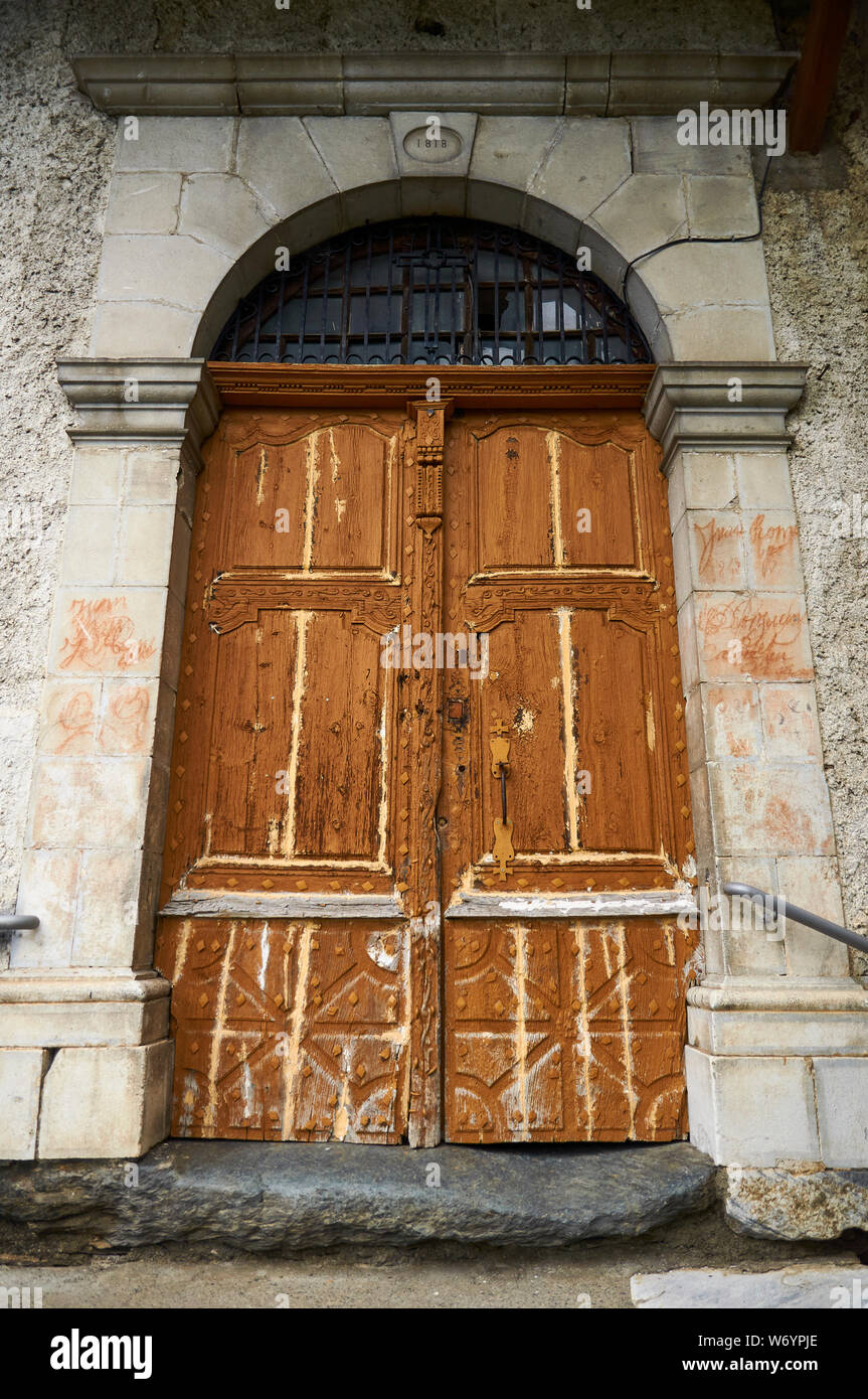 Puertas de madera antiguas y descuidadas de Sant Sernilh iglesia del siglo XIX en Canejan (valle de Arán, Lleida, Pirineos, Cataluña, España) Foto de stock