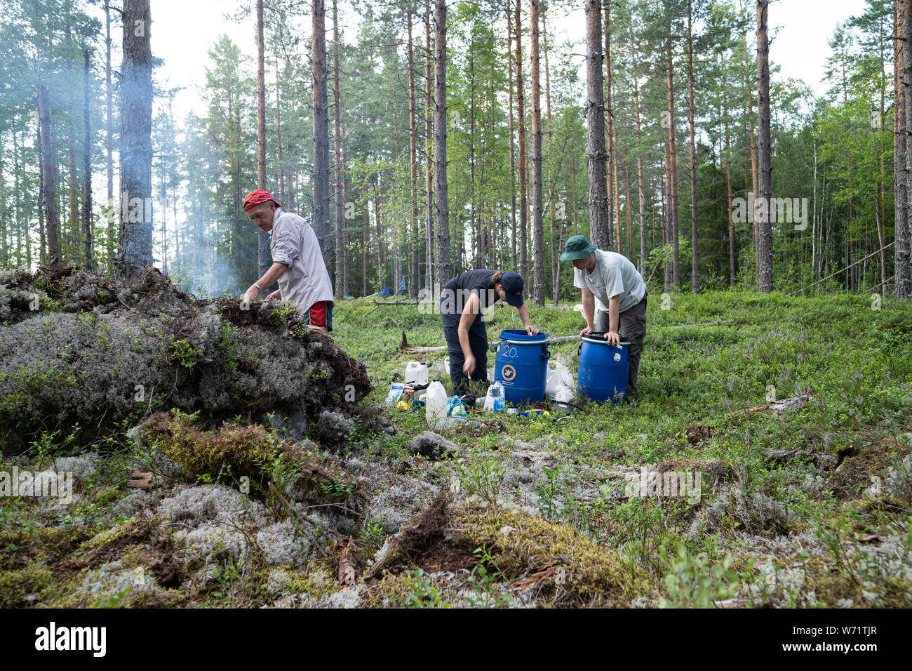 Amigos de camping salvaje en un bosque y un hombre cocinar sobre un fuego de campamento. Foto de stock