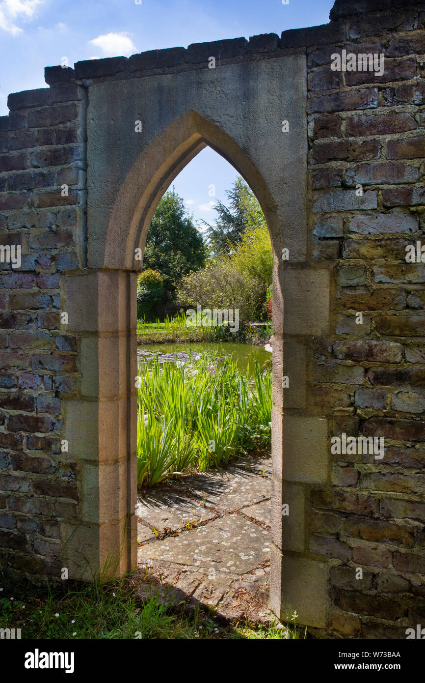 Arcada de piedra de estilo gótico en el jardín inglés, Inglaterra Foto de stock