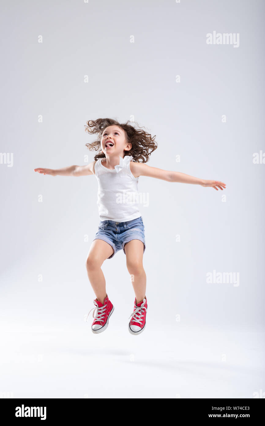Alegre niña activos energéticos en denim shorts y zapatillas rojas saltar  alto en el aire con los brazos extendidos sobre un fondo blanco con CDP  Fotografía de stock - Alamy