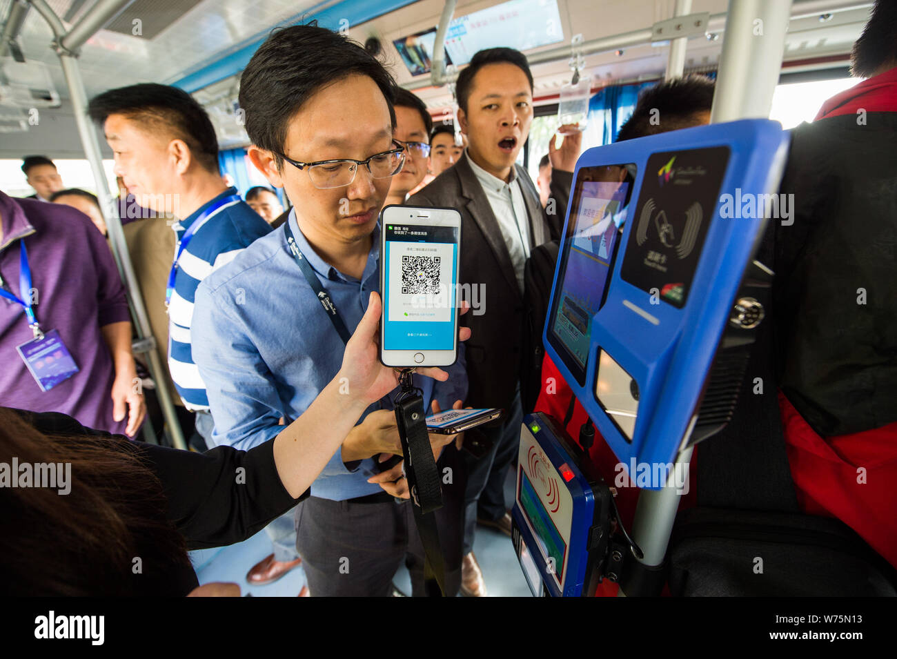 Los pasajeros pagan para billetes de autobús a través del móvil de pago Alipay Alibaba en un auto-conducir un autobús en una calle durante las operaciones de prueba en la ciudad de Shenzhen, al sur Foto de stock