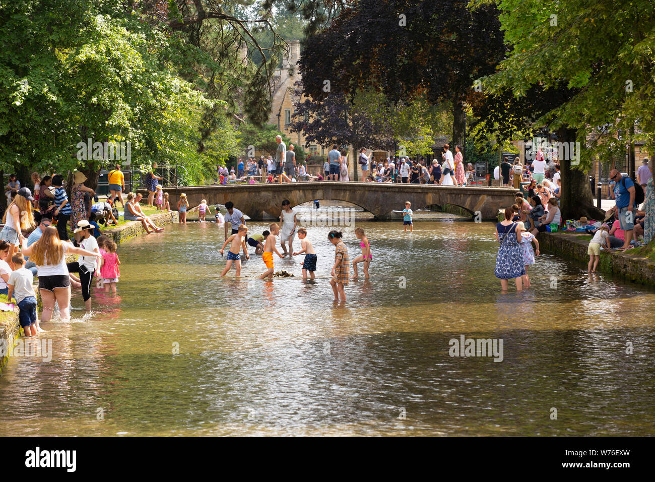 Los visitantes a la aldea de Bourton sobre el agua en el Cotswolds refrescarse en el río Windrush en el día más caluroso del año. Foto de stock