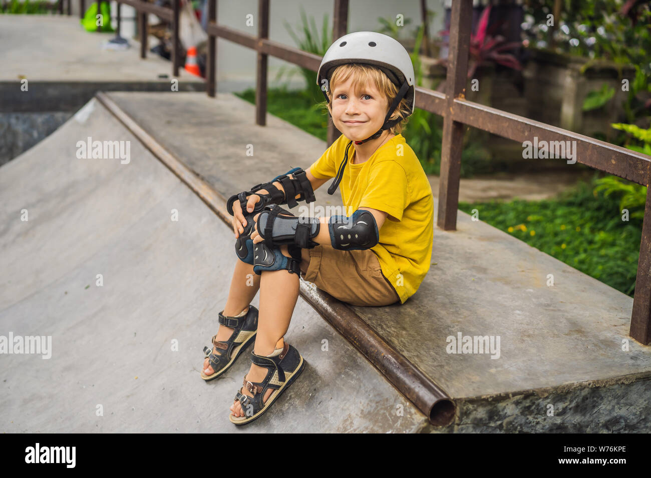 Athletic boy en casco y rodilleras aprende a monopatín en un skate
