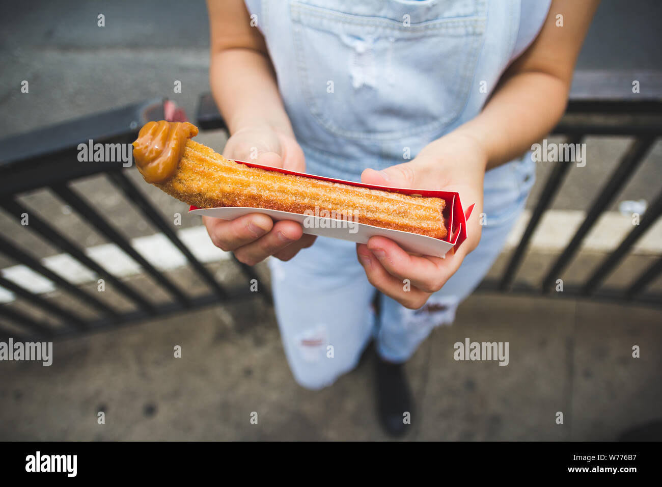 Churro. Es una masa frita hojaldre snack. Estilo brasileño con dulce de leche en la punta. En coutries popular como Portugal, España y Brasil. Mujer joven celebración swe Foto de stock