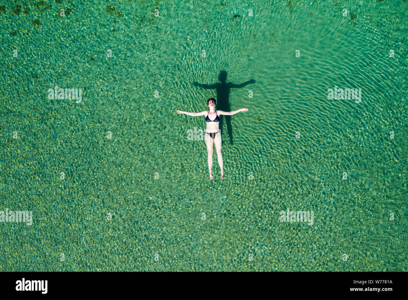 Mujer en bikini flotando en la superficie del mar en las aguas cristalinas, niña despreocupada sobre el mar, relajante, Dugi otok, Croacia Foto de stock
