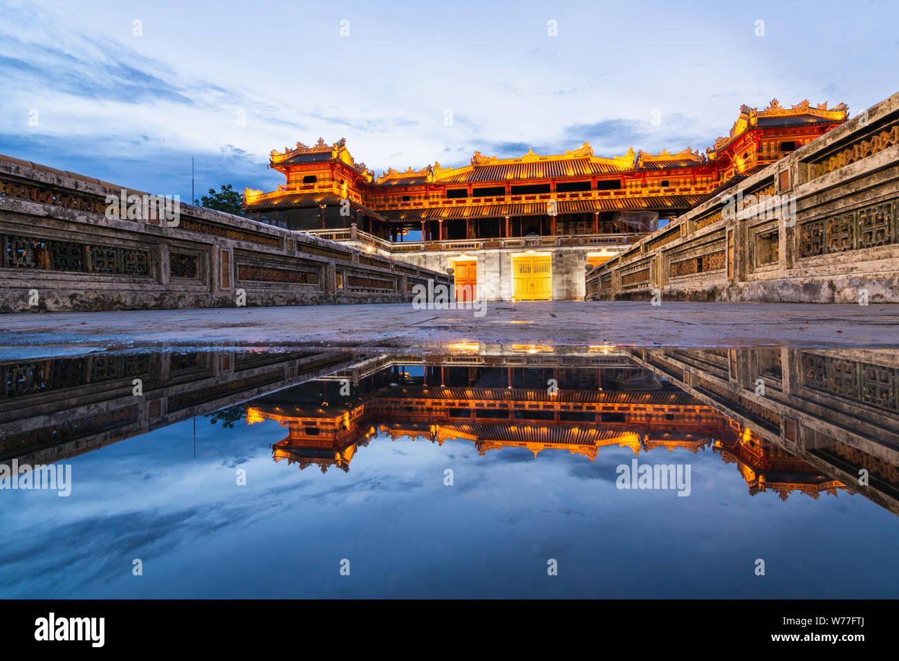 Hue, Vietnam - Junio 2019: puerta principal de la ciudad imperial prohibida púrpura al atardecer, el reflejo en el agua Foto de stock